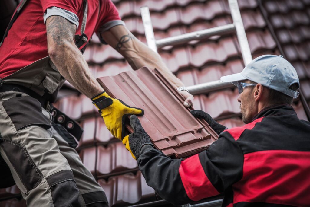 closeup of men removing roof tiles from a roof